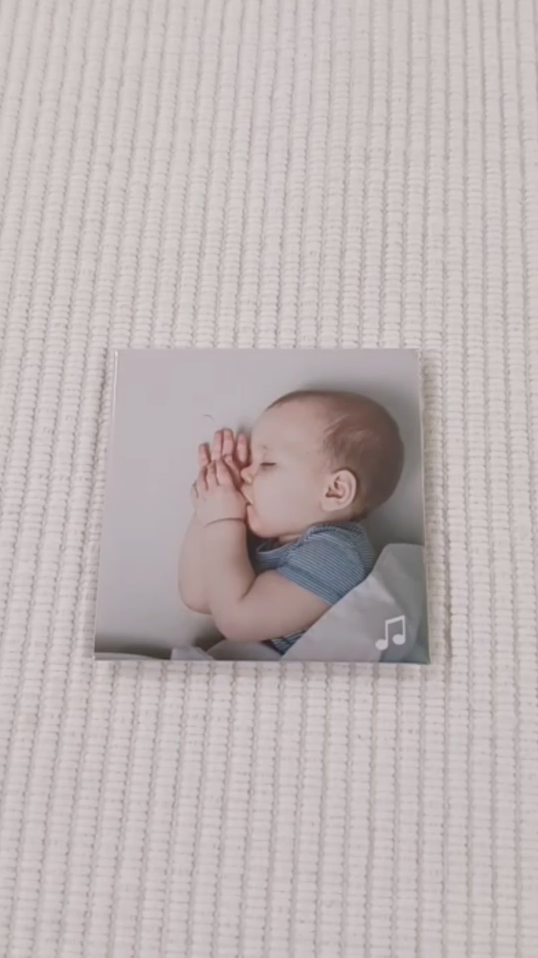 this is a video of a custom photo magnet which is a picture of a baby sleeping sweetly sucking their thumb. a finger points to a music icon in the bottom right corner and a phone then scans the magnet. a spotify link loads on the screen and You are my Sunshine song begins to play