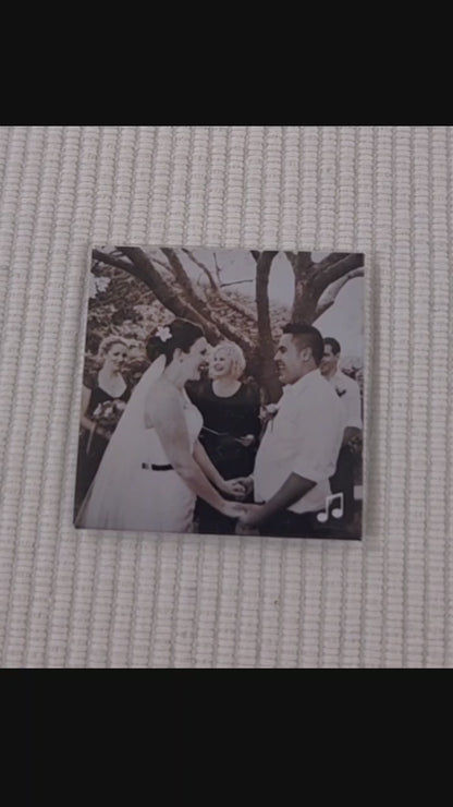 Video of a custom photo magnet which is of a couple on their wedding day. a finger points to a music logo in the bottom right corner. a phone then scans the magnet with the back of the phone and a link to a youtube video with the couple's wedding song begins to play